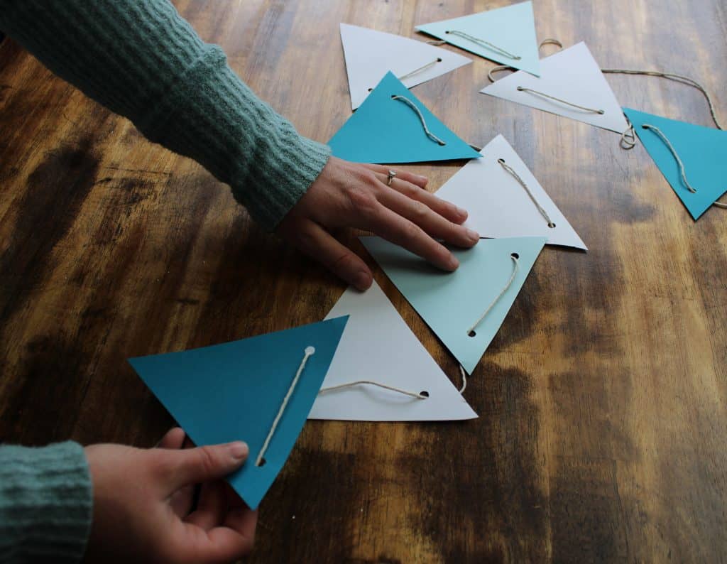 a woman spaces out the triangles on her paper bunting now that it is complete!