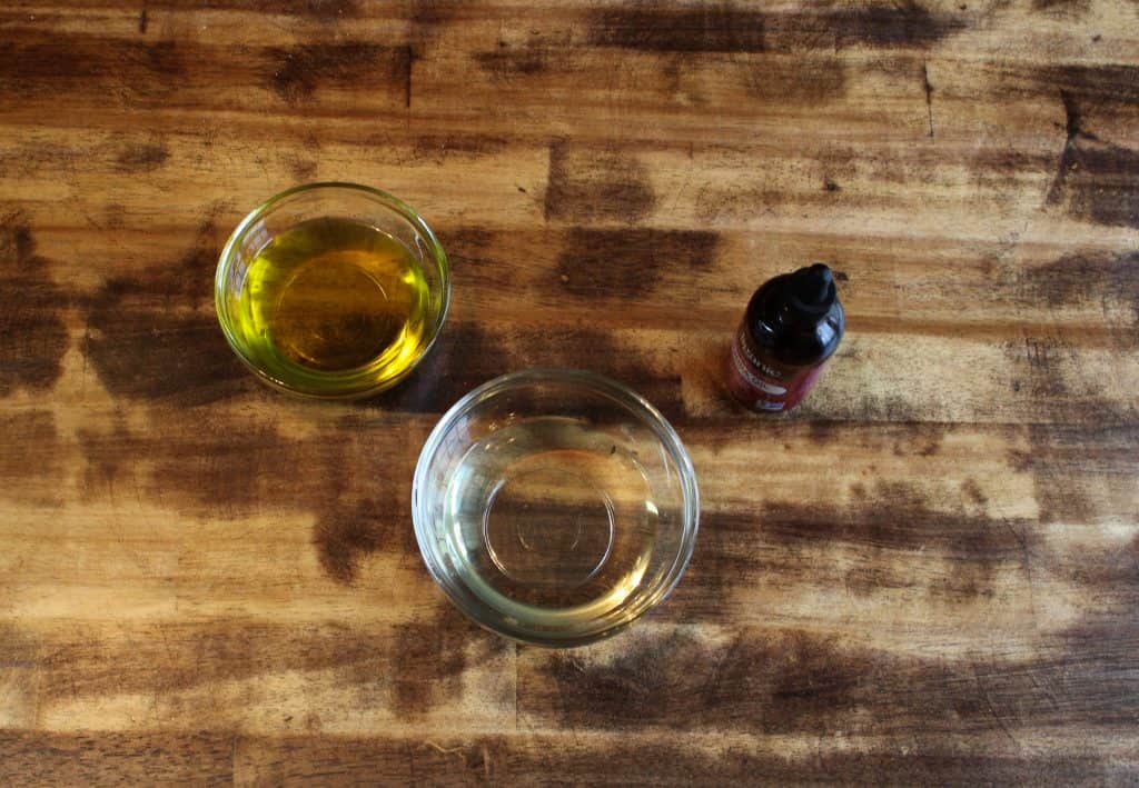 olive oil, coconut oil, and jojoba oil are displayed on a wooden table top