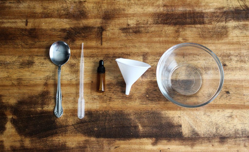 from left to right: metal spoon, pipette, amber glass dropper bottle, a white funnel, and a glass bowl
