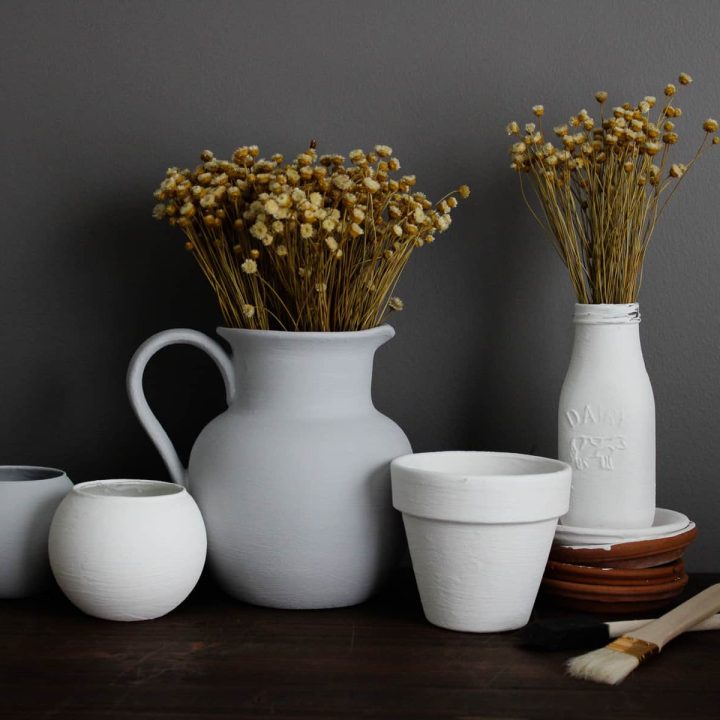 faux ceramic projects are lined up on display with dried florals