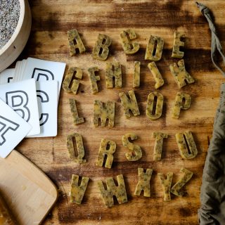 herbal beeswax letters with flashcards for matching are near a block of beeswax, dried lavender, and the cotton bag they are stored in