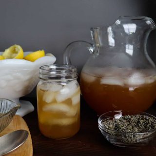 lavender honey lemonade in a glass jar next to the pitcher and lemons