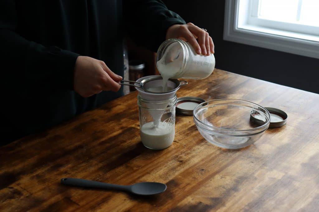 a woman separating milk kefir grains