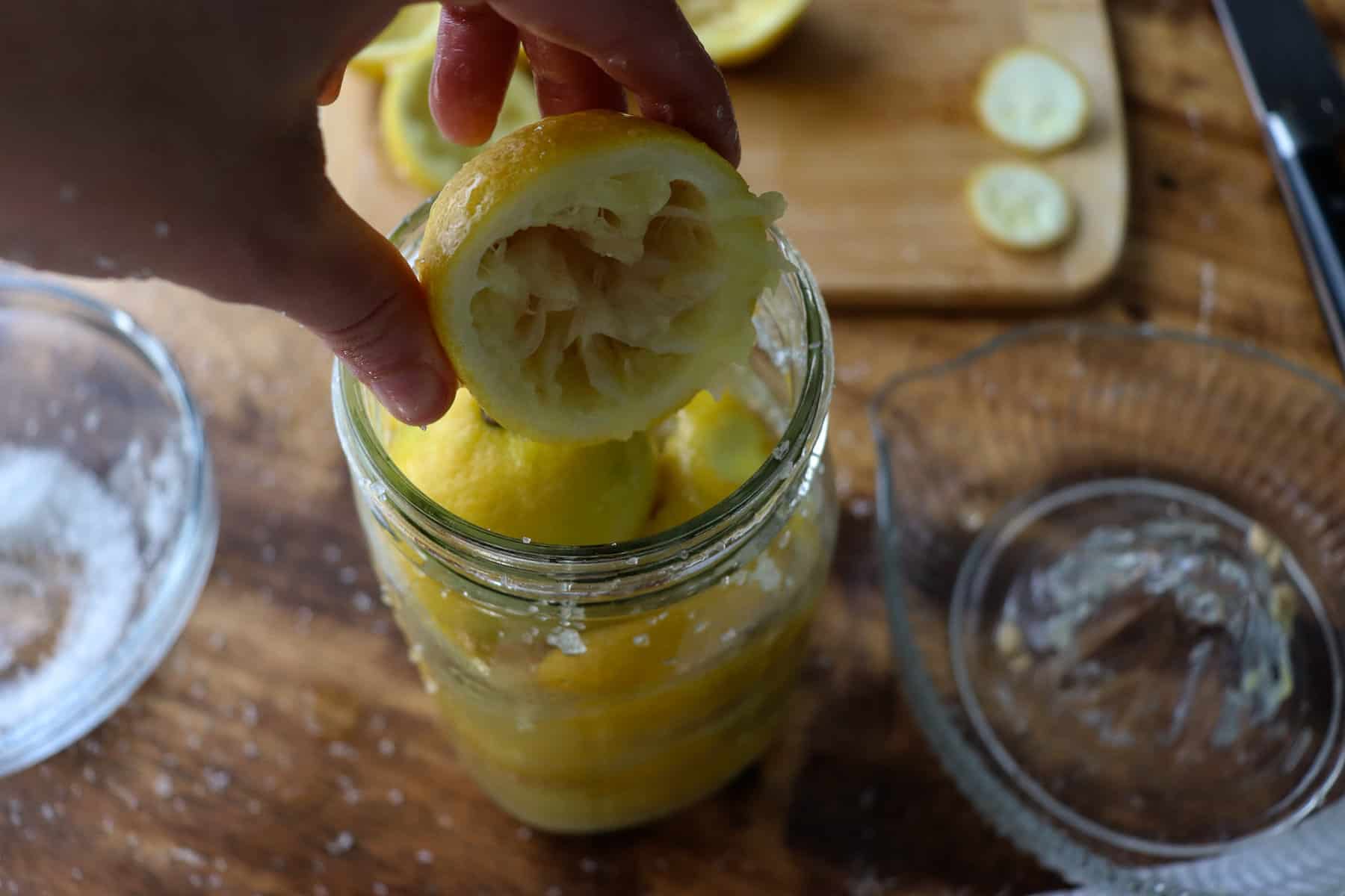 juiced lemon going into a jar of fermenting lemons