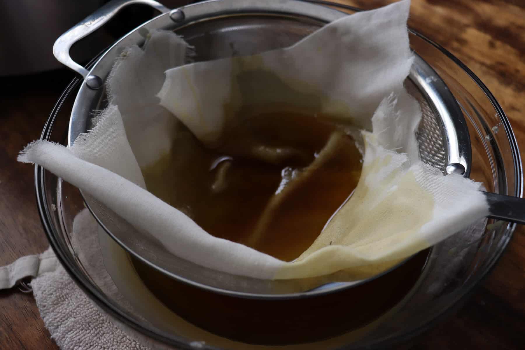 beeswax filtering through cheesecloth into a glass bowl