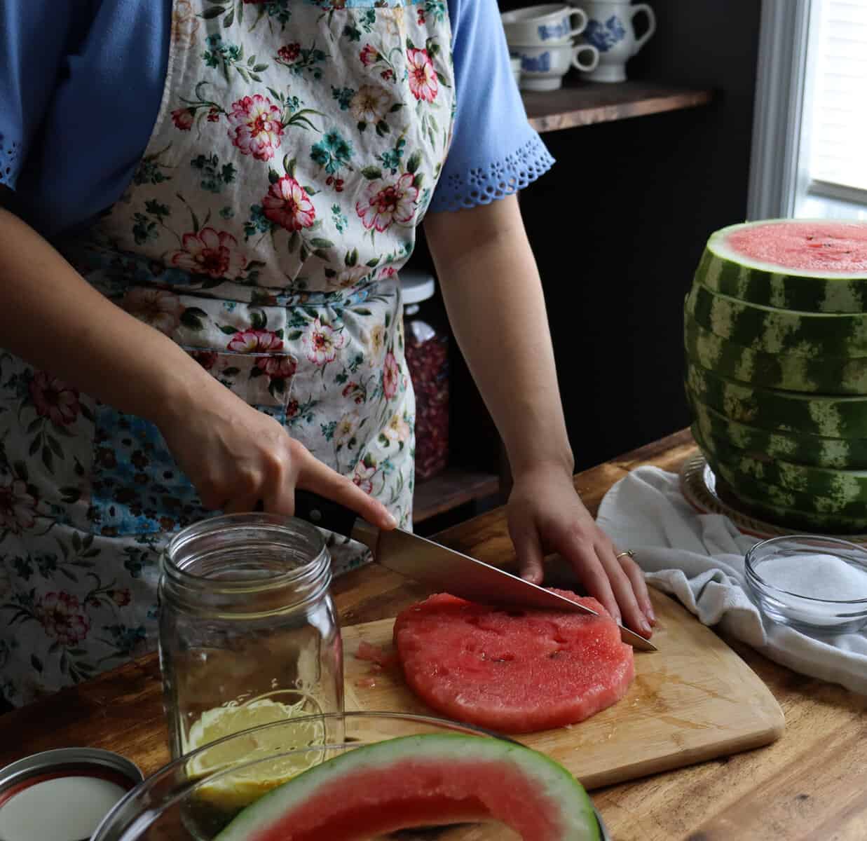 cutting the watermelon into cubes that will fit into a quart size jar