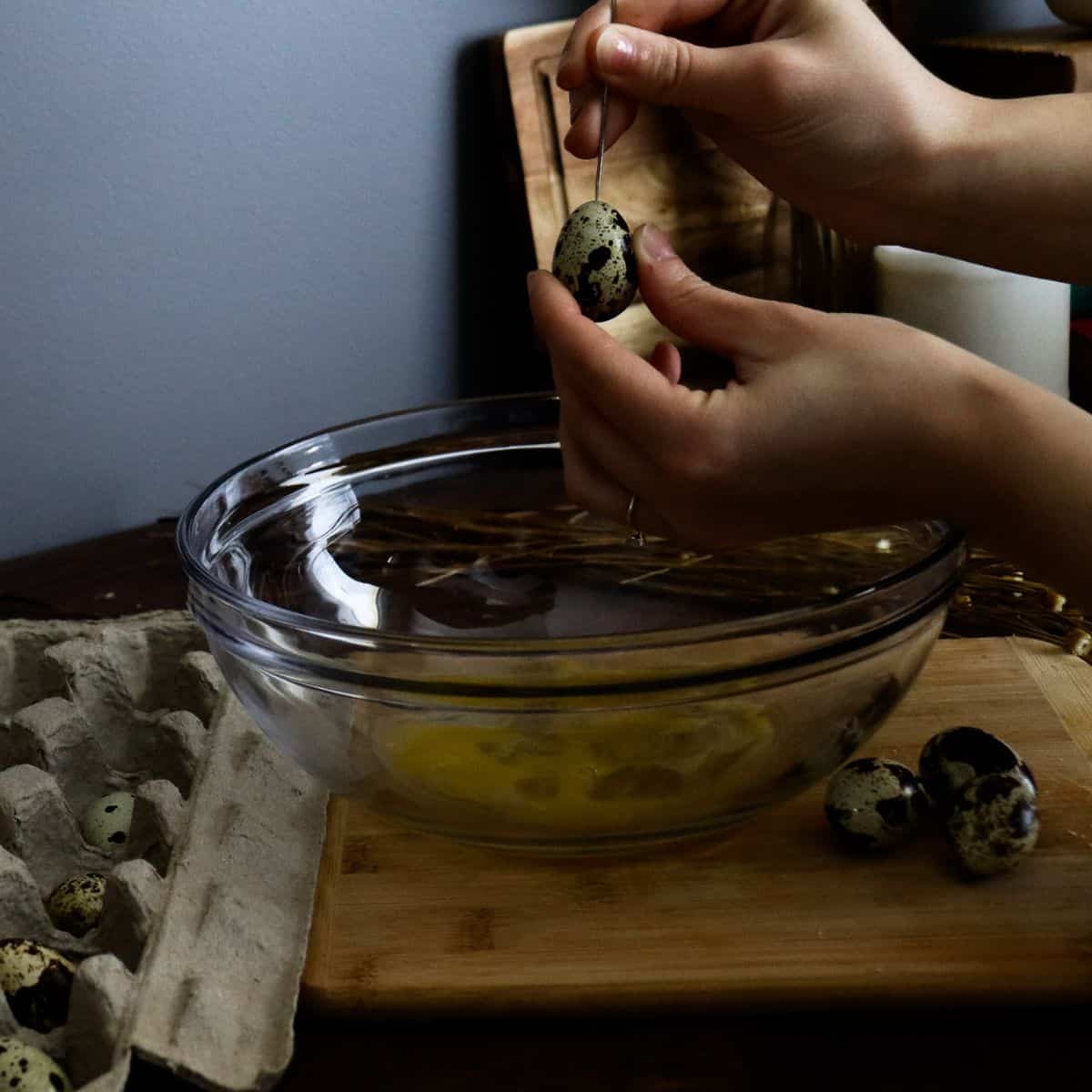 poking a hole in the top of a quail egg with a needle