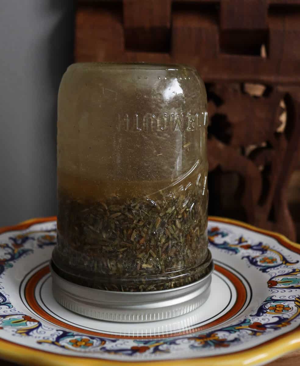 a jar flipped upside down on a plate. the honey and lavender are mixing.
