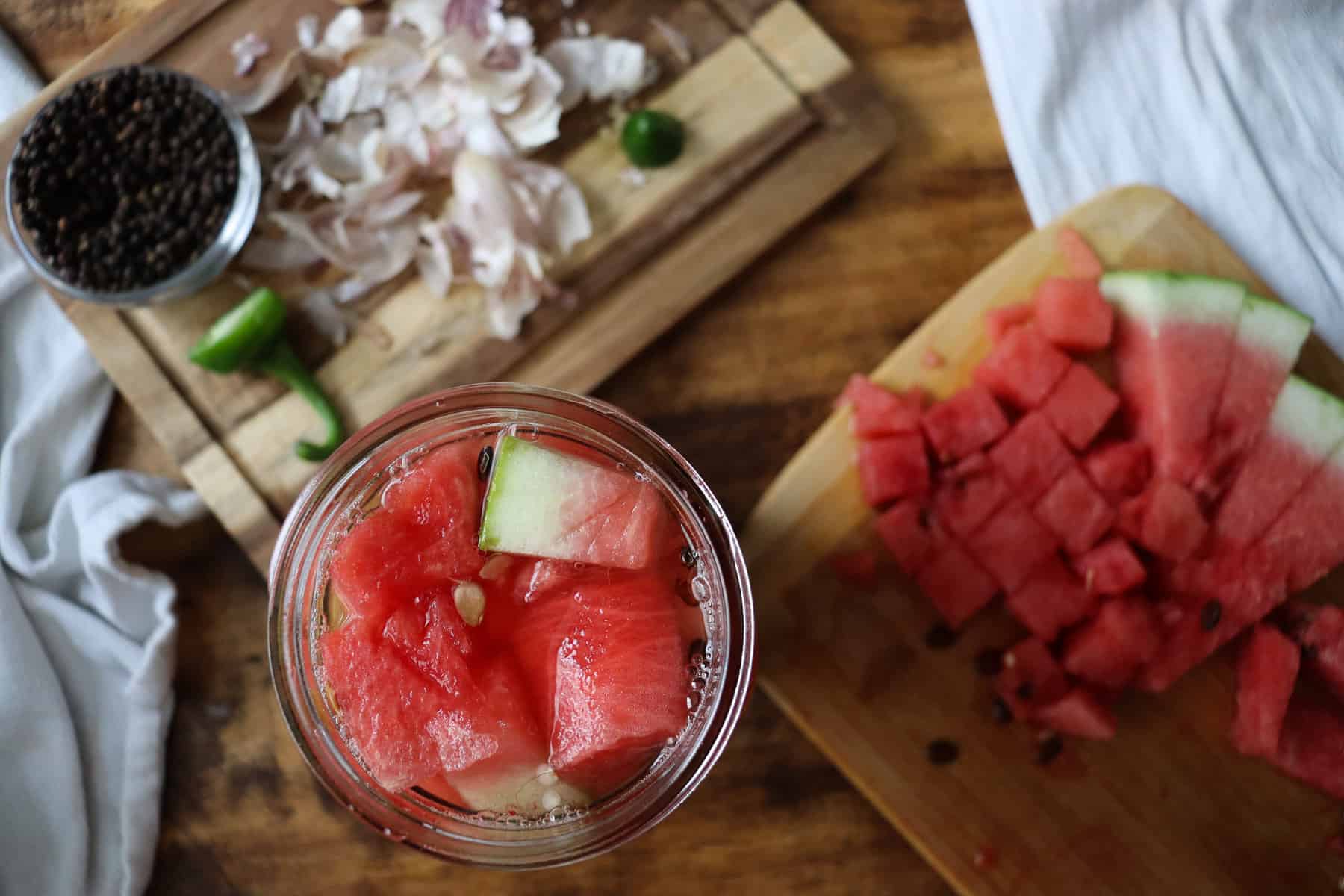 pickled watermelons in a jar next to all the ingredients used