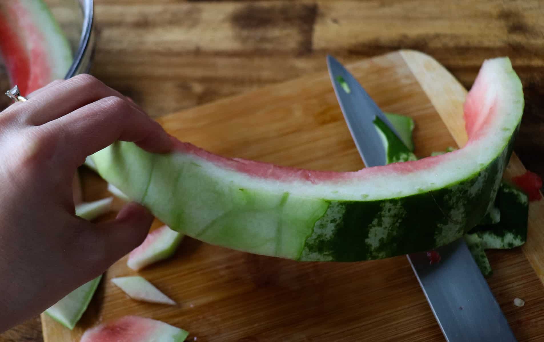 half of the watermelon rind has the outer skin removed. the other half still has it on