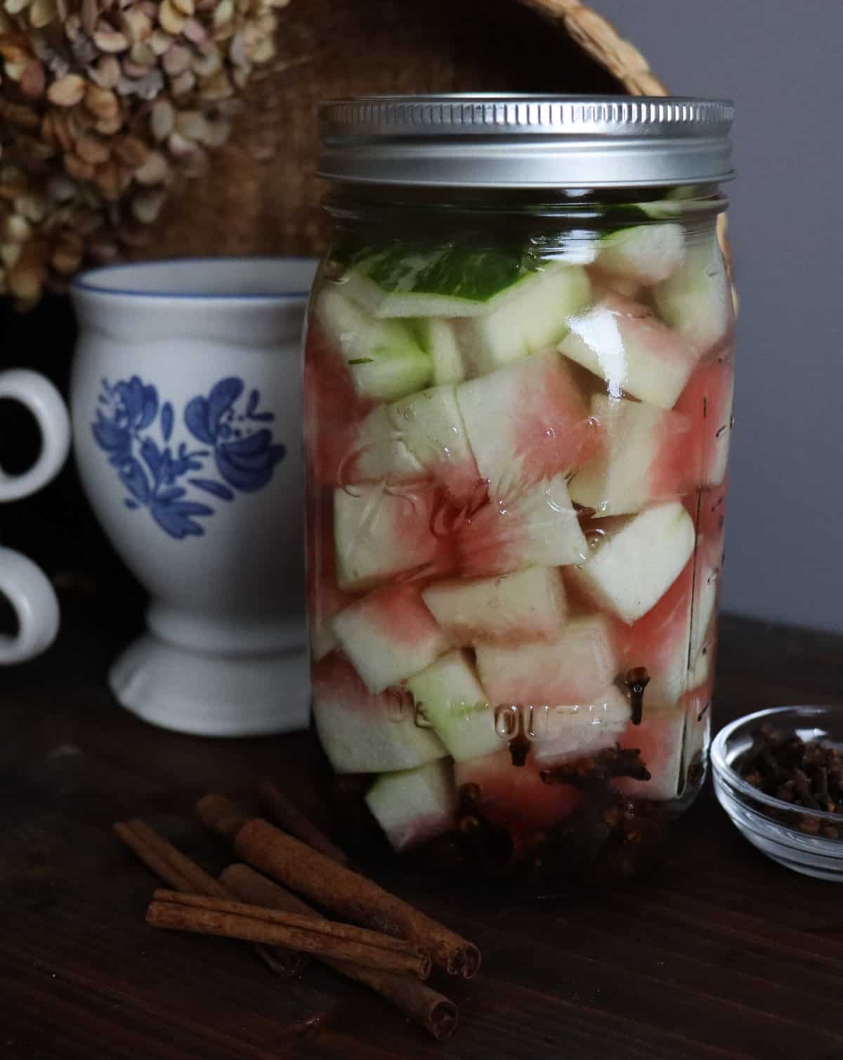 watermelon rinds pickling in a jar with cinnamon sticks and cloves