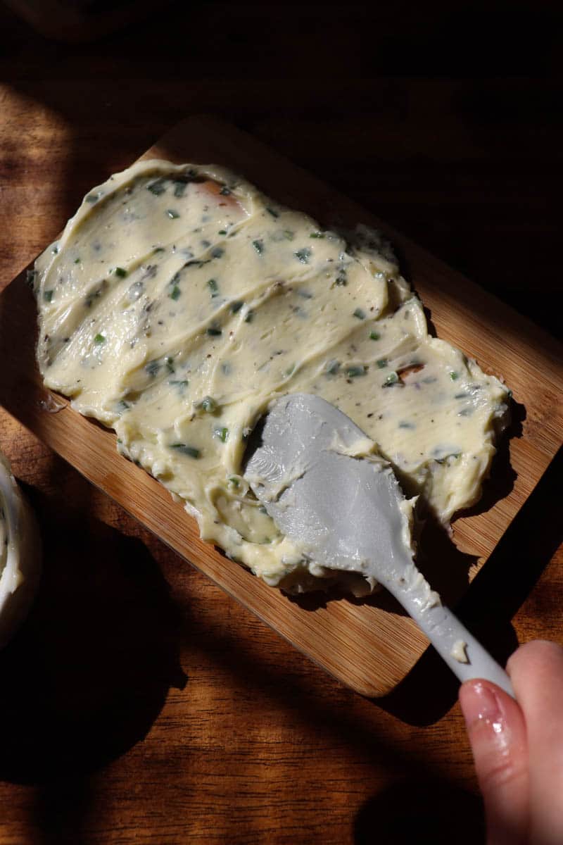 spreading herb butter on a charcuterie board turned butter board