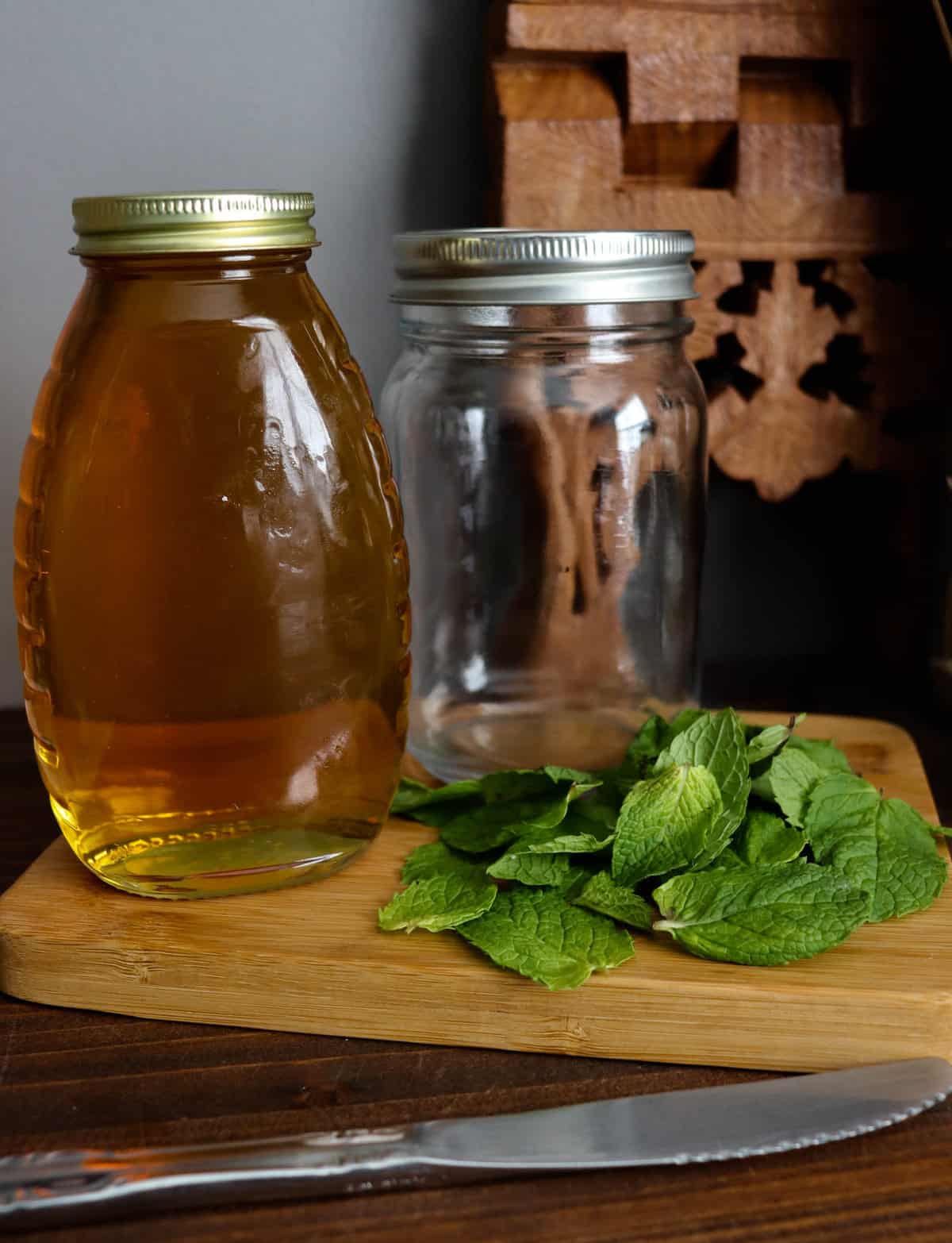 honey, mint leaves. a glass jar, and a knife