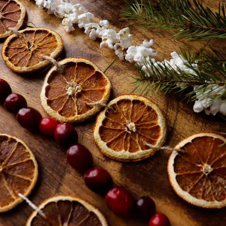 multiple other natural garlands are laid out next to two dried orange slice garlands and a pine branch