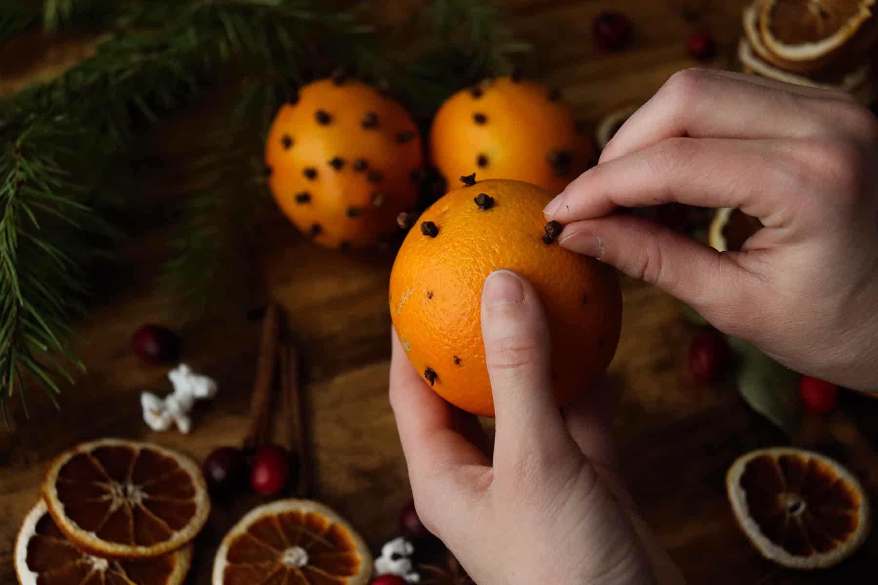 carefully placing cloves into the holes poked into the orange