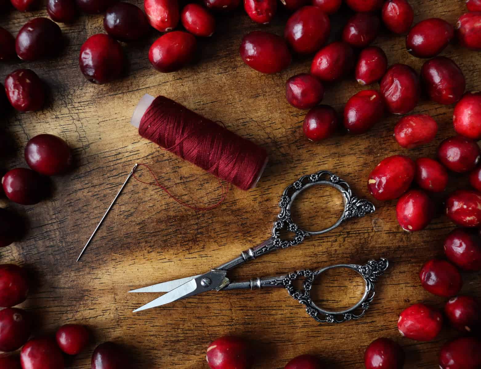 fresh cranberries, thread, a needle, and scissors.