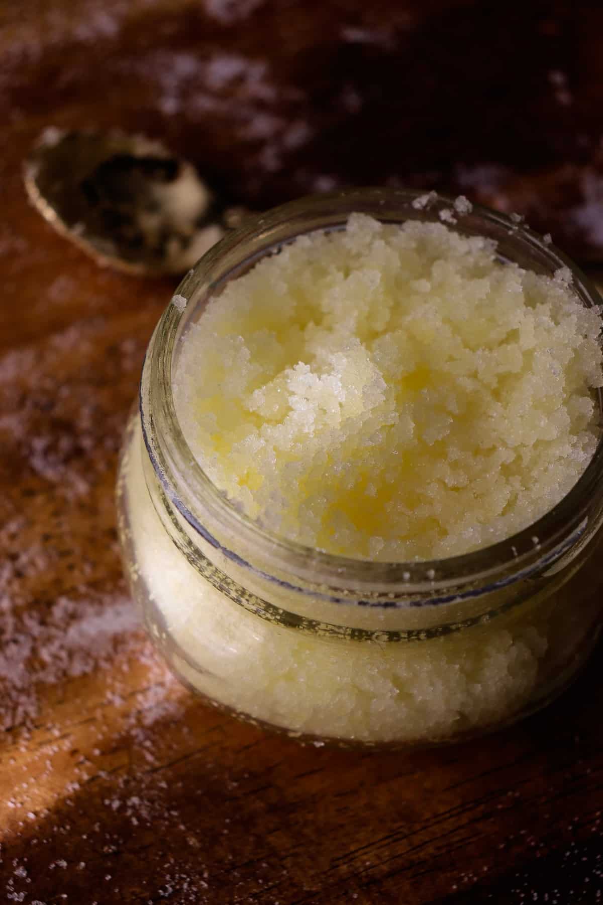 salt scrub in a glass jar with a small golden spoon nearby