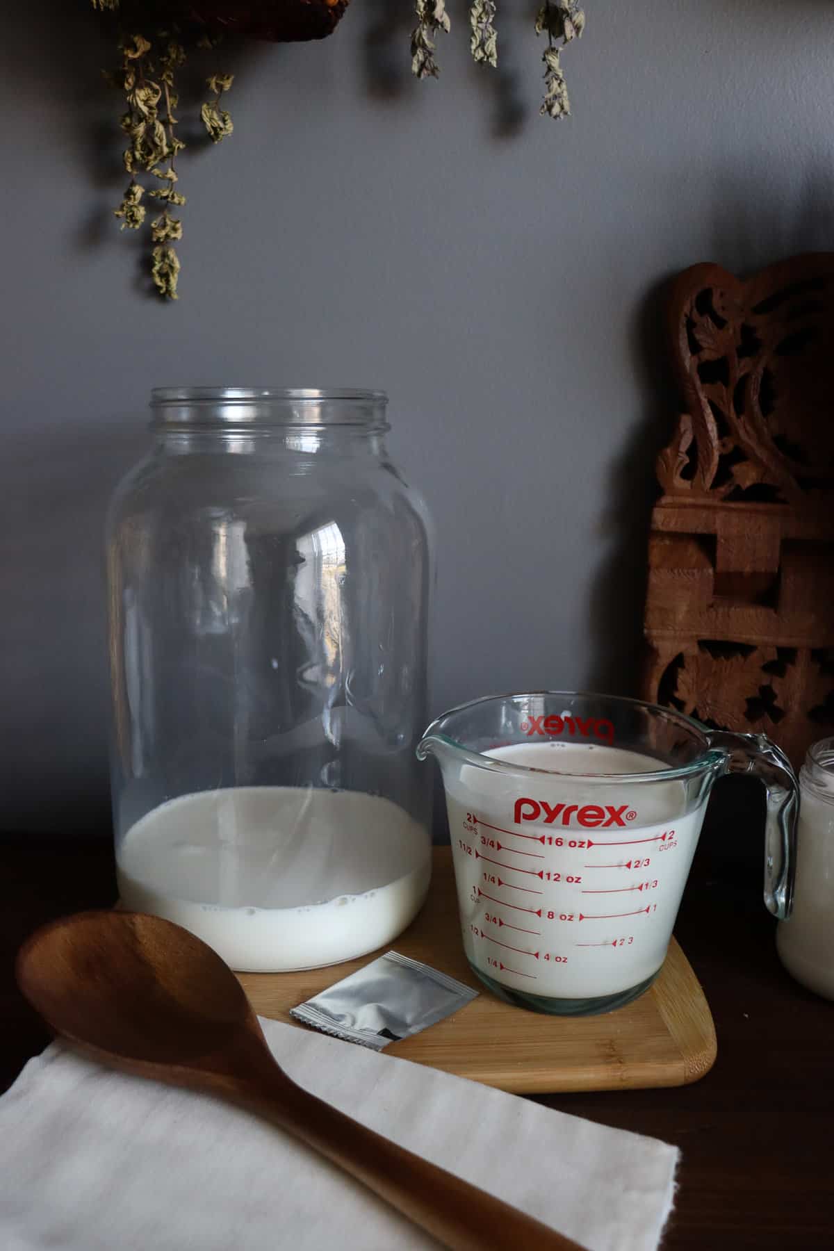 milk, heavy cream, a silver packet of starter, a wooden spoon, and cheesecloth.