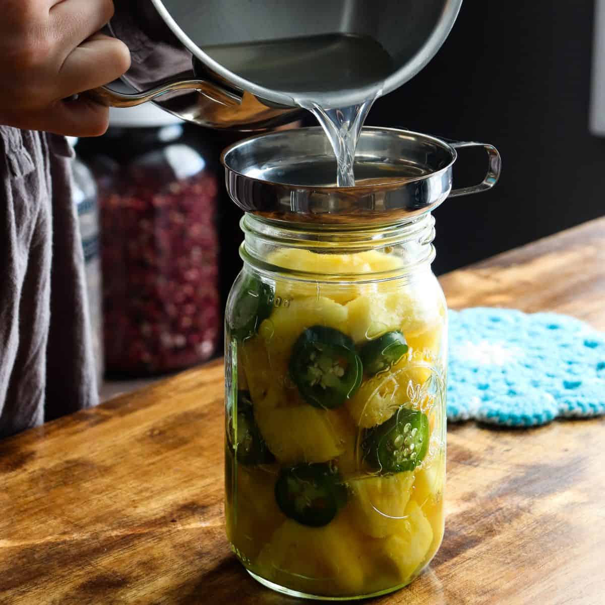 pouring brine over pineapples and jalapenos