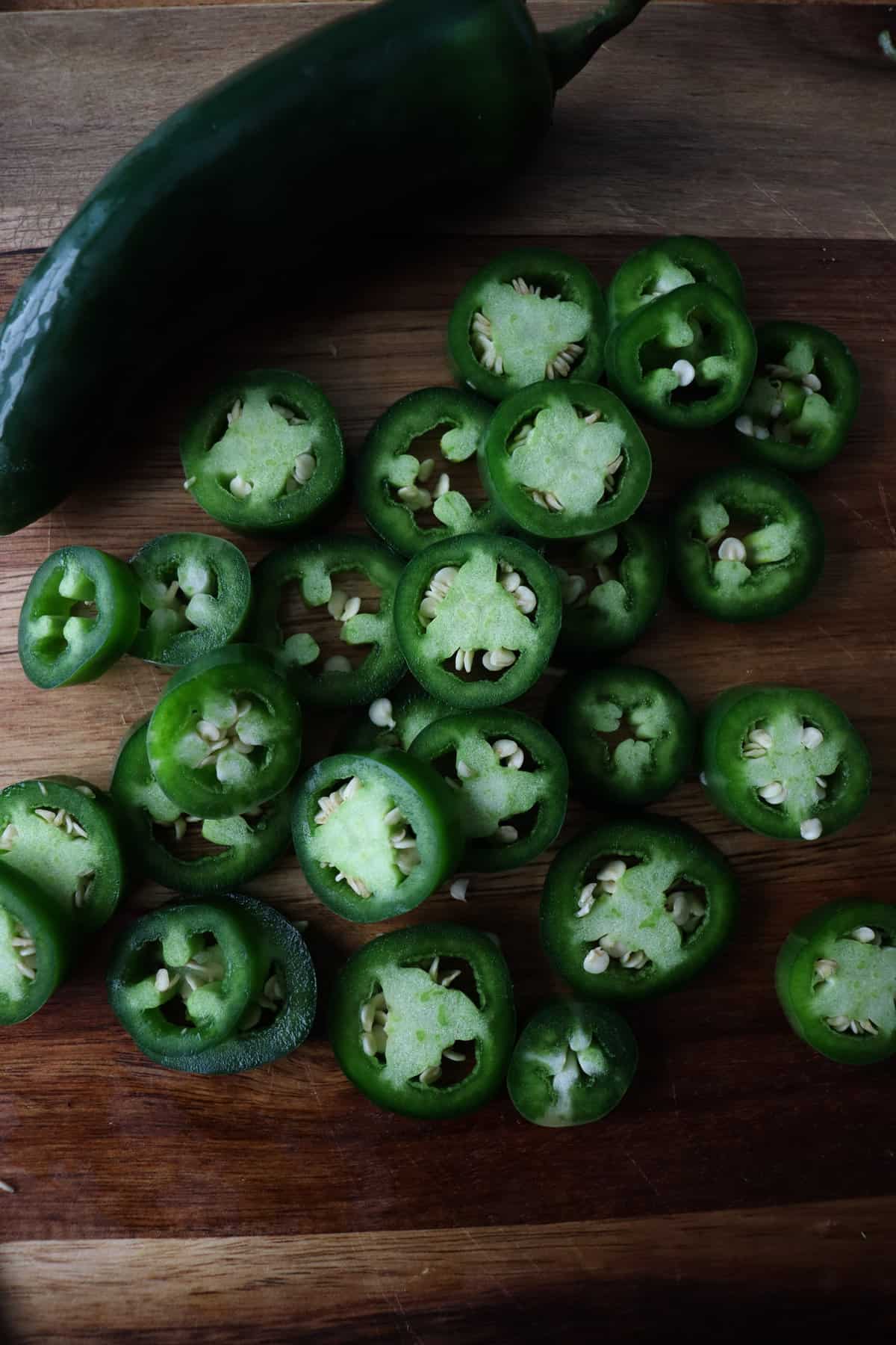 circular cut jalapeños next to a whole pepper