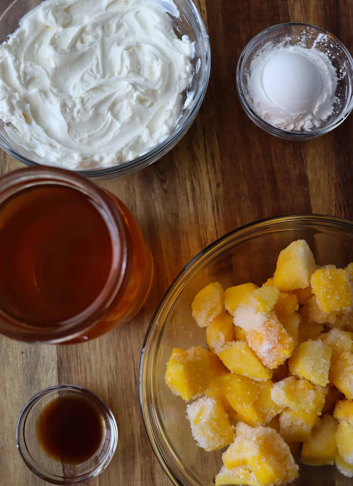 greek yogurt, arrowroot powder, honey, vanilla, and frozen mango chunks measured out